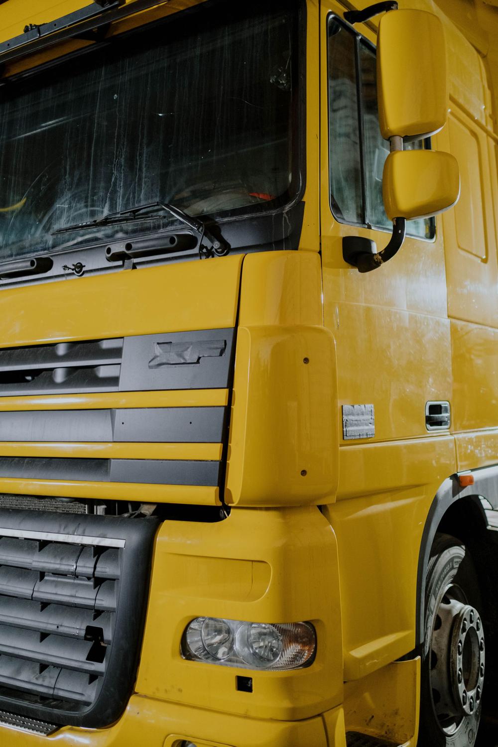 Botul unui camion galben, din față: parbrizul, oglinzile și grila.