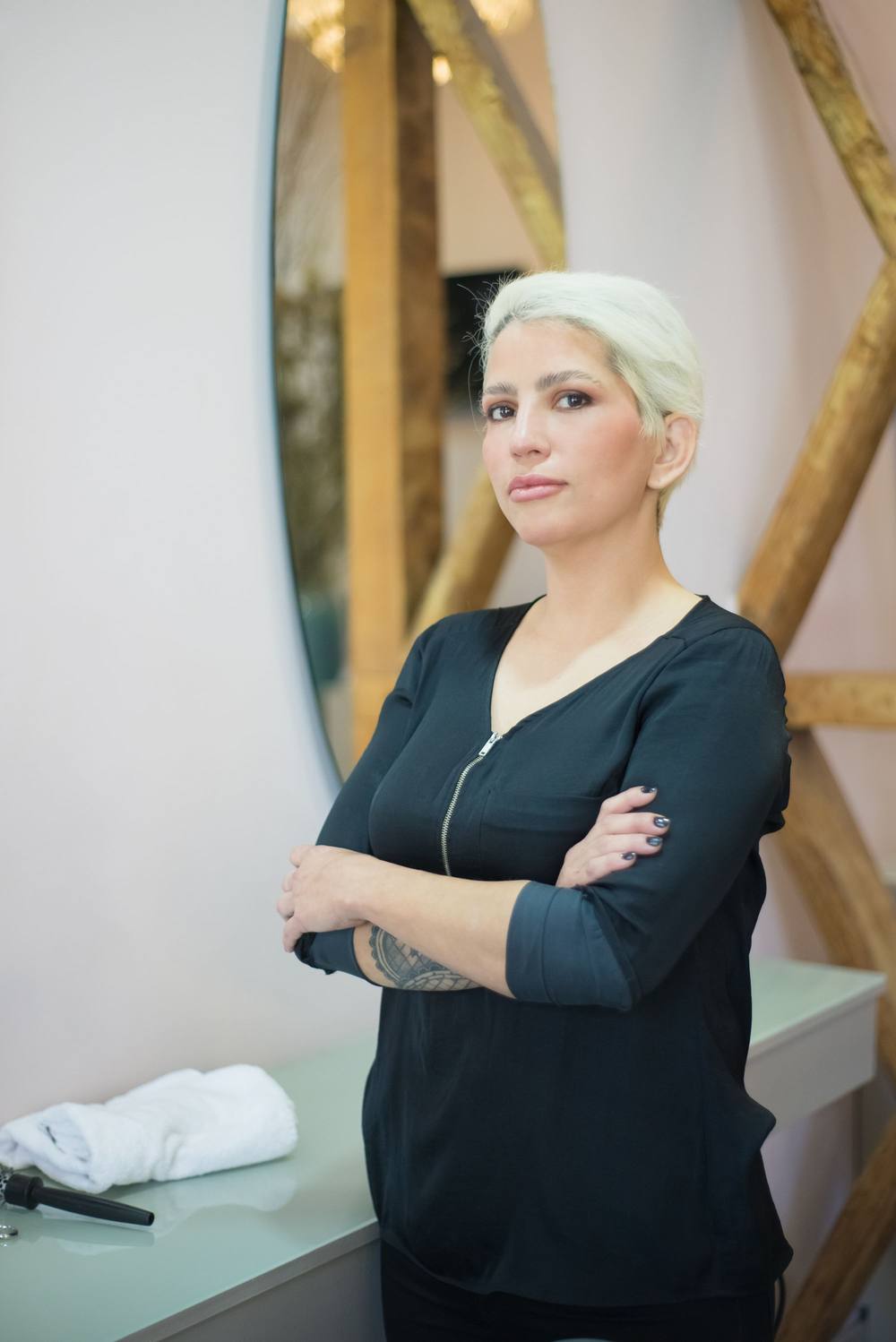 Sorina, cu brațele încrucișate, în fața unei oglinzi ovale și a grinzilor de lemn.