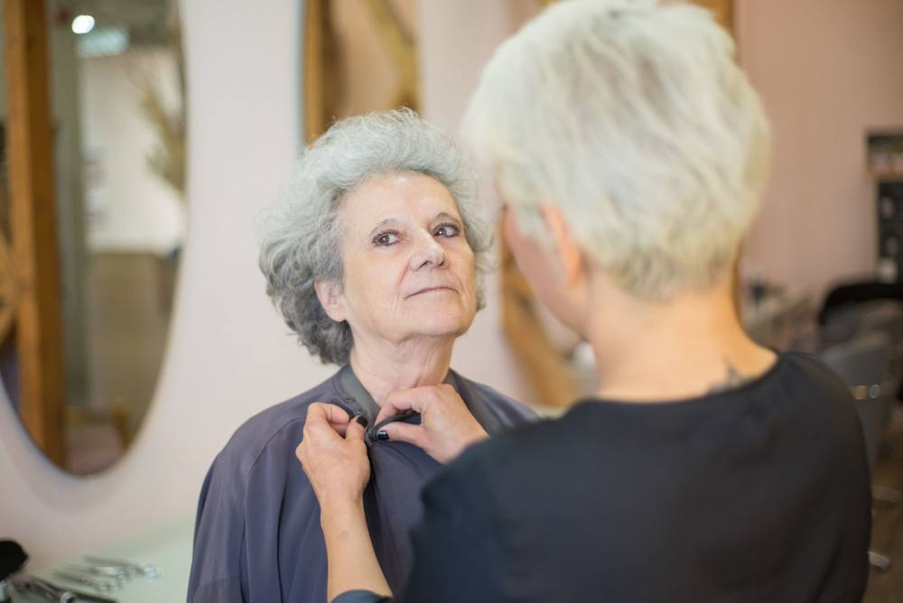 Sorina îi închide la gât pelerina gri doamnei Lia, lângă o oglindă ovală.
