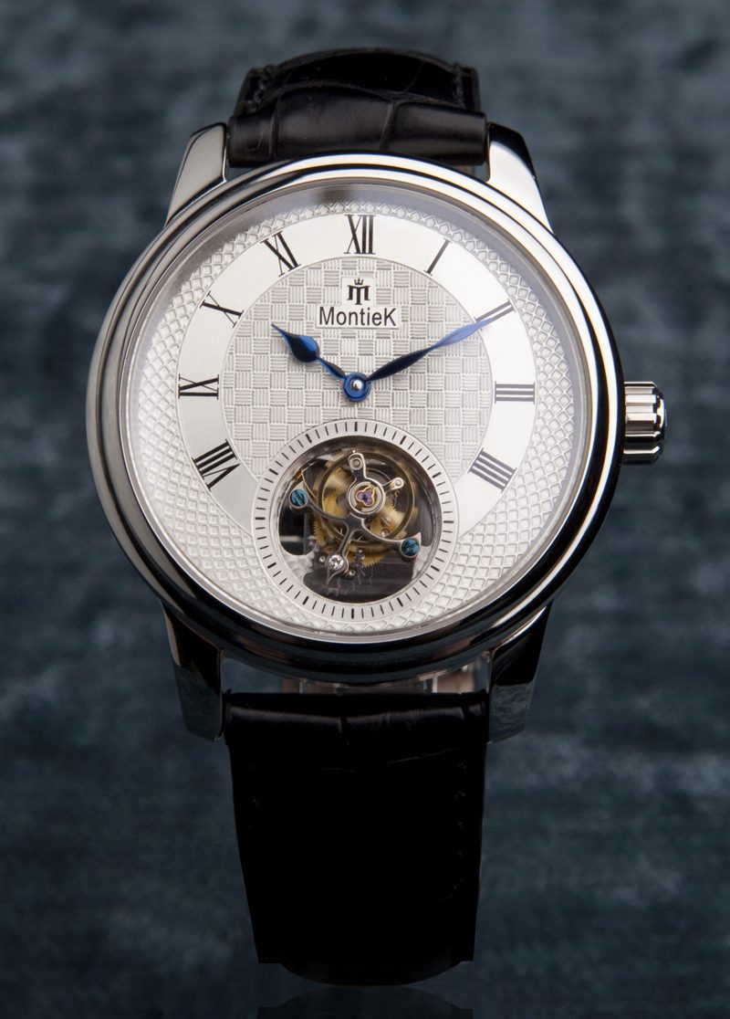 Modern stainless steel wristwatch with a visible tourbillon aperture, on a black leather strap