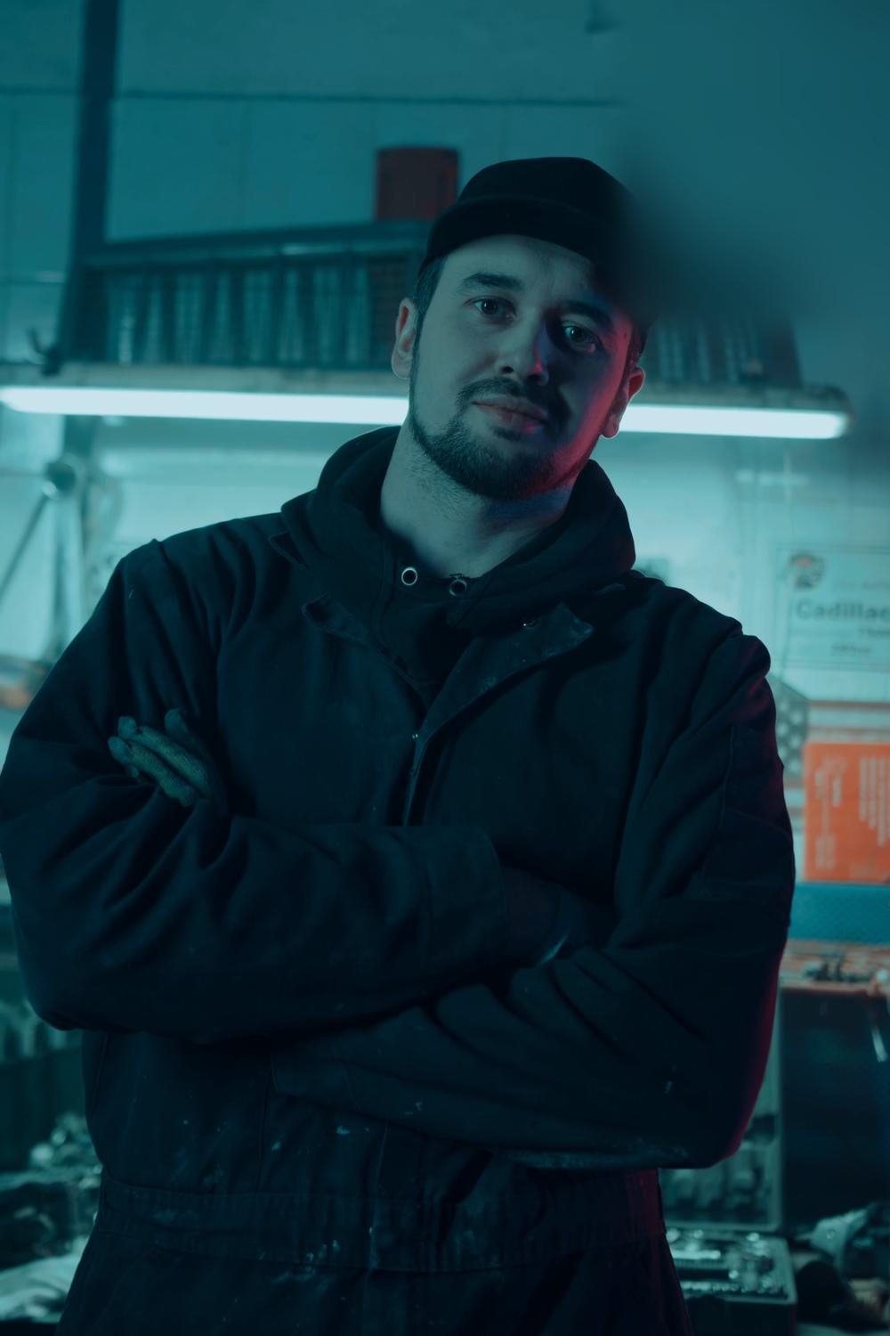 Andrei, cu brațele încrucișate, sub neonul bancului.