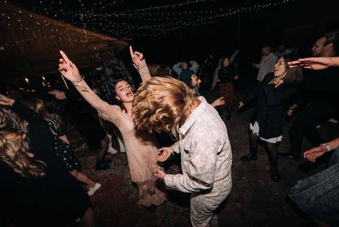 Două invitate dansează cu capul dat pe spate, cu părul în aer