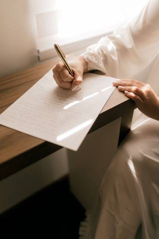 De aproape: mâna care scrie scrisoarea cu un stilou auriu