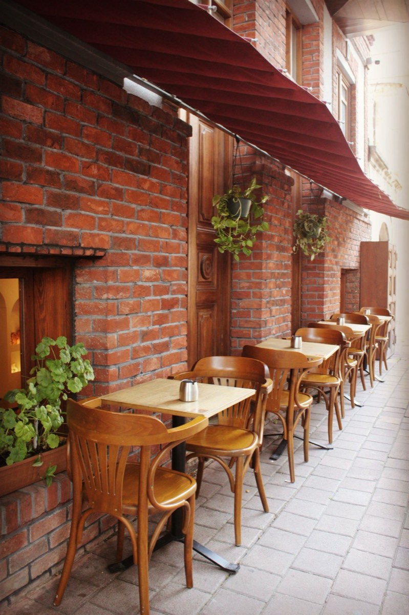 Terasa pizzeriei Vatră ziua, zid de cărămidă și plante agățătoare
